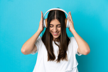 Young caucasian woman isolated on blue background listening music