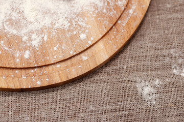 round cutting board in flour against the background of burlap