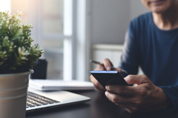 Man surfing the internet, searching information on mobile phone during working from home