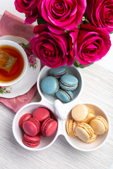 Obraz na płótnie Canvas Different types of colorful macaroons with a Cup of hot tea on white background Decorated with flowers Vintage style