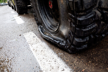 Tire with a puncture in a 4x4 vehicle, parked on a city street. © Road Red Runner