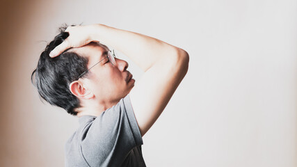 Naklejka premium Middle aged Asian man suffering from severe depression, frustrated, stress, and hopeless, putting hand on head with eyes closed, fighting with mental illness. Mental health awareness and expression.