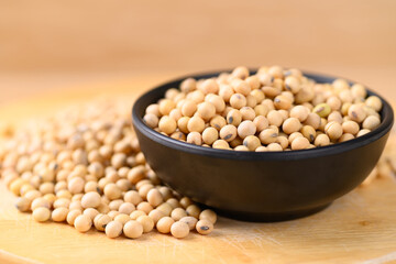 Soybean seeds in black bowl on wooden background