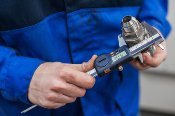 Engineer In Factory With Apprentice Checks Component Quality. Electronic caliper