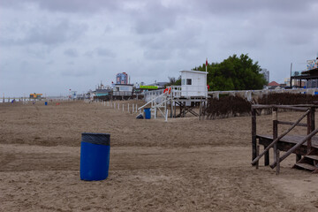 Beach without people during coronavirus. Trash can in the sand.