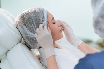 Hands of beautician doing beauty treatment for young woman