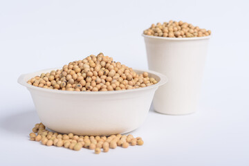 Soybean seeds in a bowl and cup on white background