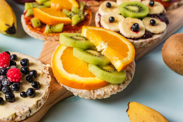 Crispy puffed rice cakes on table with fresh fruit kiwi banana apple blueberries and orange on the table - close up view on healthy organic vegetarian or vegan breakfast gluten free