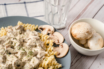 Tagliatelle Italian pasta with forest white champignon mushrooms creamy sauce and chicken or beef meat - homemade food in plate on the table top view close up