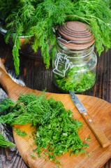 Freshly cut, green young dill chopped on a kitchen board.