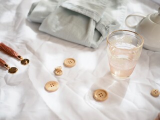 Jeans, pink glass and wooden buttons on a pretty white background.