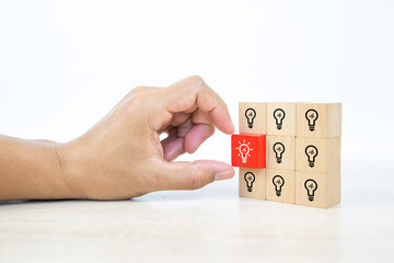 Close up hand choosing light bulb or lamp icons on cube wooden toy blocks concepts human resources for business leadership and creativity.