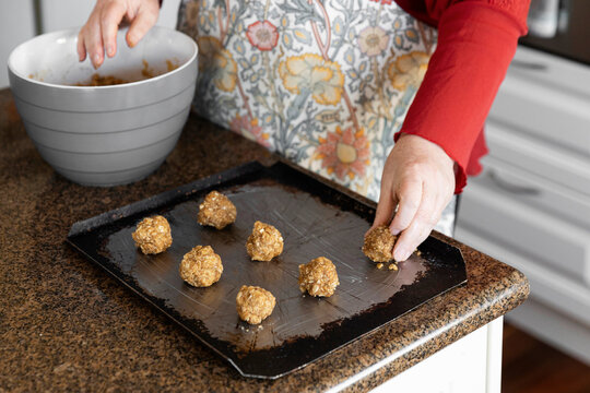 Placing anzac biscuit mix balls onto baking tray.