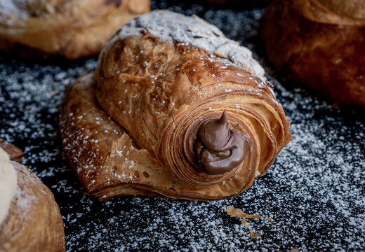 Delicious French style almond chocolatin filled with chocolate on a black table decorated with sugar.