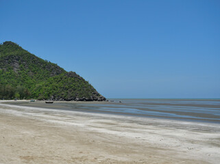 Obraz premium Sand and mud in water phenomenon, Fishing boat on the beach , Ocean waves splash the shore severely , Bay with mountain at Khao Sam Roi Yot national park , Thailand