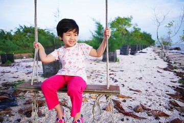 child swinging on swing.a girl is rocking in a tree on the beach
