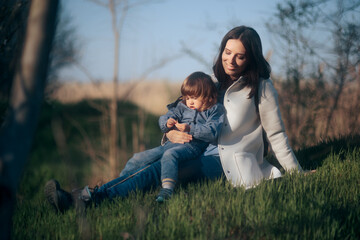 Naklejka na ściany i meble Mother Sitting in Nature with Her Child Relaxing Outdoors
