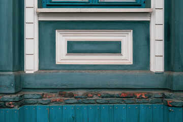 Grunge blue wall background with rough painted texture and relievo rectangle frames. Damaged brick lay and wooden plank covering in bottom part of building wall