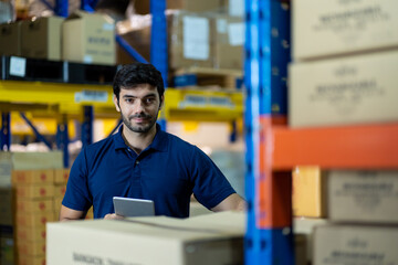 Male employee warehouse worker using digital tablet checking products or parcel goods on shelf...