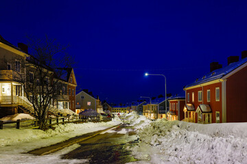 Fototapeta na wymiar Kiruna, Sweden, A Kiruna residential street at night in the spring with piles of snow.