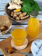 Jamu or Indonesian traditional herbal drink made from turmeric, ginger, betel leaves, tamarind, palm sugar. Healthy drink with mixed sour, sweet, and spicy taste. Ingredients in background