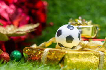 Soccer Christmas Holiday with ball and Christmas decoration on green grass background
