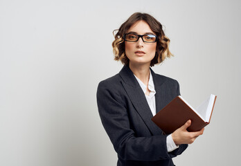 A woman in a classic suit with a book in her hands on a light background and glasses on her face business finance