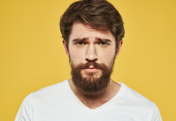 Obraz premium A brunette man with a thick beard on a yellow background emotions model