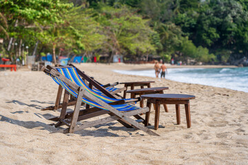Wooden table and chairs in empty beach cafe next to sea water. Close up, Thailand