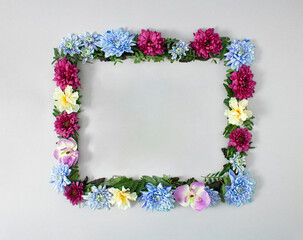 Spring floral frame  full of fresh colorful flowers and leaves. Creative flat lay concept on pastel grey background.