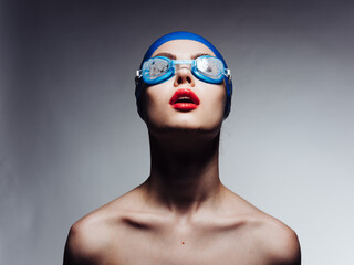 sportswoman with red lips in blue swimming cap and glasses looking up cropped view