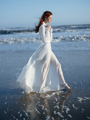 Fototapeta na wymiar romantic woman in full length sundress by the ocean blue sky beach
