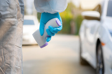 Medical staff with PPE use infrared thermometer gun on road.