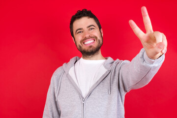 Naklejka premium young handsome caucasian man in sports clothes against red wall directs fingers at camera selects someone. I recommend you. Best choice