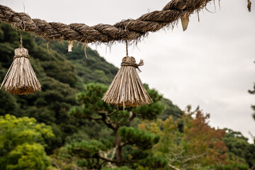 Japanese Shimenawa with Onusa (Haraikushi) hanged traditional torii gate in Shinto shrine. An Onusa (Nusa) is a wooden wand used in Shinto rituals. Asian oriental, zen, rural, nostalgia concept