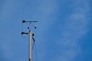 Wind direction meter. Radio system on steel column, blue sky.