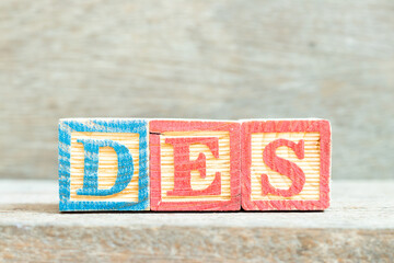 Color alphabet letter block in word DES (Abbreviation of Delivered Ex Ship) on wood background