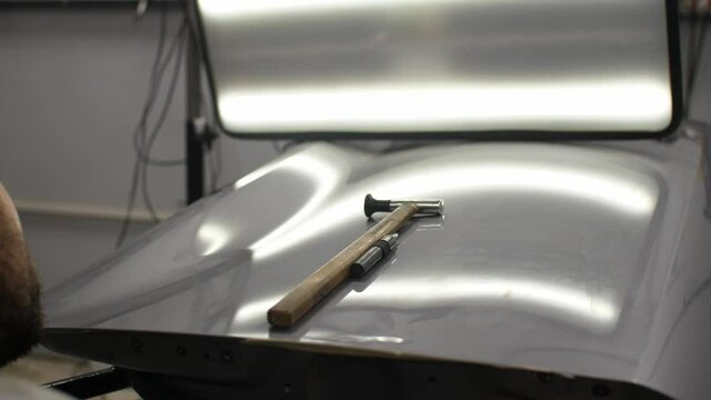 Looking on the perfect silver colored car surface filmed from perspective of workers back after repair using modern dent removing technology that don't needed to paint gives better quality chipper 