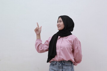 Portrait of smiling asian muslim women looking sideways pointing to copy space on white background. Beautiful asian woman with casual dress. Beautiful muslim women.