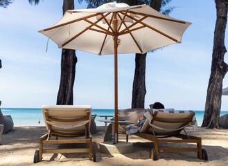 Sun beds with umbrellas on the beach of resort. Summer vacation.