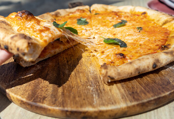 Woman hand taking slice of vegetarian pizza fresh from the pizza oven. Italian cuisine.