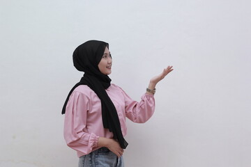 Cute young asian muslim women looking sideways and pointing to copy space. Beautiful asian woman with casual dress. Beautiful muslim women.