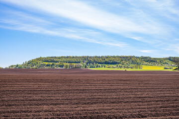 Fototapeta na wymiar Plowed field at a table hill in a rural landscape at spring