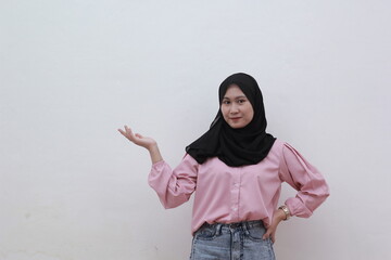 Smiling young asian muslim woman touching her hip and pointing to copy space. Beautiful asian woman with casual dress. Beautiful muslim women.