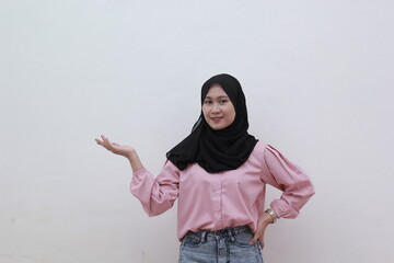 Portrait of cheerful young asian muslim woman pointing to copy space. Beautiful asian woman with casual dress. Beautiful muslim women.