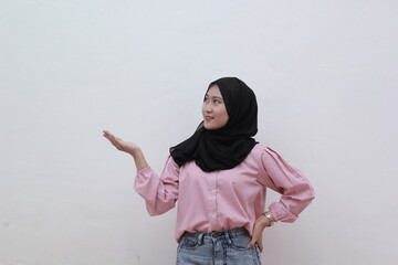 Cute asian woman with hand on hip and pointing to copy space by looking sideways. Beautiful asian woman with casual dress. Beautiful muslim women.