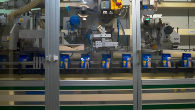 Moving of a pasta packs on a conveyor line with automatic closer. Industrial scene from a food factory