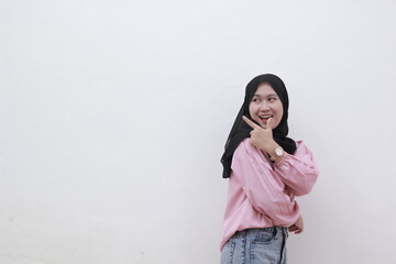 Portrait of happy asian muslim woman looking sideways and pointing to copy space. Beautiful asian woman with casual dress. Beautiful muslim women.