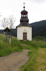 chapel in a mountain landscape with meadow and path