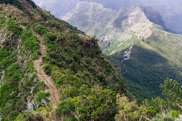 The best hiking routes in Madeira. Beautiful landscape of green mountains with trails. Small figure of man.
